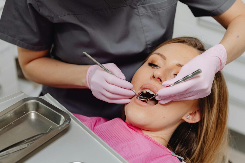Dentist performing check-up on female patient in a clinic setting, emphasizing dental care.